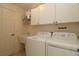 Well-lit laundry room with white washer, dryer, cabinets, utility sink and door at 17194 Se 85Th Willowick Cir, The Villages, FL 32162