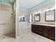 Bathroom features a walk-in shower, soaking tub, double vanity, and decorative mirrors at 17427 Se 72Nd Overbrook Ct, The Villages, FL 32162