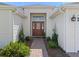 Elegant front entrance with a decorative glass door, lush landscaping, and a brick pathway at 17427 Se 72Nd Overbrook Ct, The Villages, FL 32162