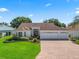 Charming single-story home with a well-manicured lawn, brick driveway, and three-car garage at 17427 Se 72Nd Overbrook Ct, The Villages, FL 32162
