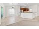 Open-concept living room with tiled floors and view into kitchen featuring granite countertops and wood cabinetry at 17427 Se 72Nd Overbrook Ct, The Villages, FL 32162