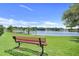 Scenic view of community lake with a park bench under a blue sky at 1761 Country Terrace Ln, Apopka, FL 32703