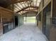 View of the open barn interior with concrete floors and wood beam architecture, showing open doorway to outdoor view at 19621 Lake Lincoln Ln, Eustis, FL 32736