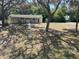 Ranch-style home surrounded by mature trees, featuring a walkway and expansive front lawn at 19621 Lake Lincoln Ln, Eustis, FL 32736
