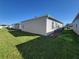 Side yard view featuring a well-maintained lawn, vinyl siding, and partial home exterior at 1978 Lockett Ln, The Villages, FL 34762