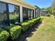 Stucco home exterior featuring manicured shrubs, green grass and large sliding windows overlooking a lush lawn at 1985 Abordale Ln, The Villages, FL 32162