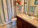 Bathroom featuring a wood vanity with solid surface countertop, decorative mirror, and striped shower curtain at 1985 Abordale Ln, The Villages, FL 32162