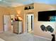 Open main bedroom featuring a decorative shelf, wall-mounted TV and access to other rooms at 1985 Abordale Ln, The Villages, FL 32162