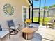 Relaxing screened-in patio with outdoor seating and decorative sunburst wall art at 1985 Abordale Ln, The Villages, FL 32162