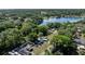 Aerial view of the property surrounded by lush trees, a lake nearby, and the neighborhood at 201 W Mirror Lake Dr, Fruitland Park, FL 34731