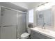 Bright bathroom featuring a glass door shower, gray vanity, and decorative mirror at 201 W Mirror Lake Dr, Fruitland Park, FL 34731