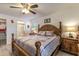 This main bedroom features a wooden bed frame, ceiling fan, ensuite bath, and two windows for ample light at 201 W Mirror Lake Dr, Fruitland Park, FL 34731
