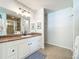 Bathroom vanity with granite countertop, framed mirror, lighting fixture, and a walk-in shower in the background at 203 Se 30Th Ave, Ocala, FL 34471