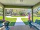 Inviting covered front porch featuring an American flag and views of the meticulously kept front lawn and circular drive at 203 Se 30Th Ave, Ocala, FL 34471