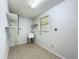 Bright laundry room with a sink, a window, tile floor, and storage shelves at 203 Se 30Th Ave, Ocala, FL 34471
