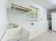 Laundry room with utility sink, shelf, window and tile flooring at 203 Se 30Th Ave, Ocala, FL 34471