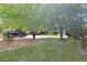 Well maintained lawn with mature trees providing shade and lush landscaping with a blue SUV parked in the driveway at 20631 Prince Ranier Pl, Leesburg, FL 34748