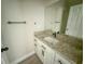 Modern bathroom vanity with granite countertop, white cabinets, and a decorative mirror, alongside a closed door at 217 S East St, Leesburg, FL 34748