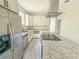 Modern kitchen with white cabinets, granite countertops, stainless steel appliances, island cooktop, and tile flooring at 217 S East St, Leesburg, FL 34748