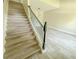 Elegant staircase featuring wood-look tile steps, complemented by black iron railings and modern pendant lighting at 217 S East St, Leesburg, FL 34748
