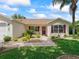 A cozy home featuring a red front door, complemented by lush greenery, and a convenient two-car garage at 2259 Lockwood Loop, The Villages, FL 32162