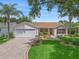 Charming single-story home with a well-manicured lawn, lush landscaping, and brick paver driveway at 2259 Lockwood Loop, The Villages, FL 32162
