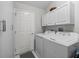 Bright laundry room with white washer and dryer, storage cabinets, and convenient access door at 2259 Lockwood Loop, The Villages, FL 32162