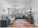 Comfortable living room with hardwood floors, white sofa, and a view of the landscaped front yard at 2259 Lockwood Loop, The Villages, FL 32162