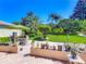 A lush backyard with manicured lawn, mature trees, patio dining set, and privacy hedges at 24436 Madewood Ave, Leesburg, FL 34748