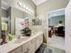 Bathroom featuring double sinks, marble countertops, decorative fixtures, and neutral paint, with view to bedroom at 24436 Madewood Ave, Leesburg, FL 34748