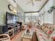 A cozy sunroom featuring wicker furniture, tile flooring, and large windows overlooking a well-manicured yard at 24436 Madewood Ave, Leesburg, FL 34748