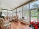 A cozy sunroom featuring wicker furniture, tile flooring, and large windows overlooking a well-manicured yard at 24436 Madewood Ave, Leesburg, FL 34748