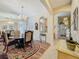 Elegant dining room with a chandelier, table, decorative rug, and an arched entry to the front door at 25523 Maurepas Ln, Leesburg, FL 34748