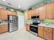 Kitchen area with stainless steel appliances and wood cabinets at 25523 Maurepas Ln, Leesburg, FL 34748
