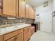 Bright laundry room with ample cabinet storage, mosaic tile backsplash, sink and adjacent tiled mudroom at 25523 Maurepas Ln, Leesburg, FL 34748