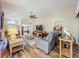Spacious living room featuring comfortable seating, wood-look floors, ceiling fan, and access to other living areas at 25523 Maurepas Ln, Leesburg, FL 34748