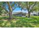 Serene backyard featuring mature trees, a patio area, and lush greenery, ideal for relaxing and entertaining at 26736 Cash Ct, Leesburg, FL 34748