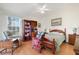Bright bedroom with wood floors, ceiling fan, a cozy reading chair and ample bookshelf space at 26736 Cash Ct, Leesburg, FL 34748
