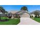 Well-maintained home featuring a brick driveway, attached garage, and beautifully landscaped front yard at 3049 Saint Thomas Ln, The Villages, FL 32162