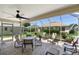 Screened lanai with a fan, multiple seating areas, and a brick floor for relaxing outdoors at 3049 Saint Thomas Ln, The Villages, FL 32162