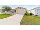 Single story home with an attached garage and a concrete driveway, green lawn and shrubbery at 312 Emmalee Pl, The Villages, FL 32162