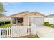 Single story home with front porch, concrete driveway, garage and green lawn with white picket fence at 312 Emmalee Pl, The Villages, FL 32162