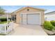 Close up view of a one story home with an attached garage, concrete driveway, and partial white picket fence at 312 Emmalee Pl, The Villages, FL 32162