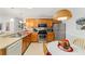 Well-equipped kitchen featuring wood cabinets, stainless steel appliances, and a cozy breakfast nook with a modern woven lamp at 312 Emmalee Pl, The Villages, FL 32162