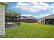Landscaped backyard with screened patio, lush green grass, and a brown privacy fence at 3329 Boyd Cir, Oxford, FL 34484
