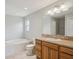 Primary bathroom featuring a soaking tub, tiled floors, and a granite vanity at 3329 Boyd Cir, Oxford, FL 34484