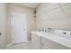 Laundry room boasts white appliances, tile flooring, wire rack, and utility sink at 3329 Boyd Cir, Oxford, FL 34484