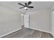 A clean bedroom with wood-look floors, a ceiling fan, and a white paneled door at 3415 Sail Fish Ave, Fruitland Park, FL 34731