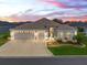 Stunning single-story home featuring a three-car garage, manicured lawn, and beautiful landscaping at dusk at 4406 Creighton Loop, The Villages, FL 32163