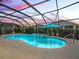 Evening shot of a screened-in pool with a waterfall feature and lush greenery adding a layer of privacy to the pool area at 4406 Creighton Loop, The Villages, FL 32163